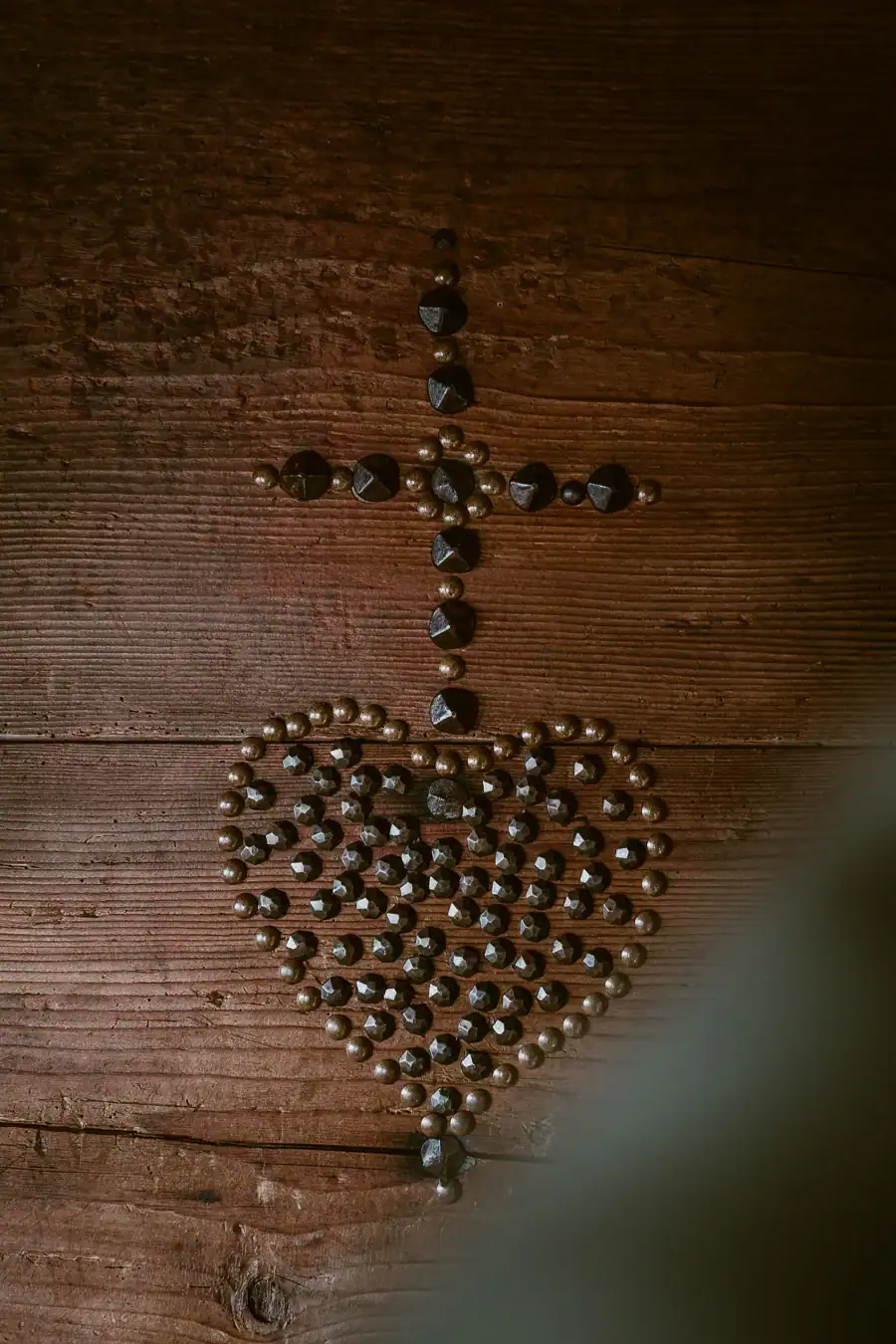 Motif traditionnel r&eacute;alis&eacute; avec des clous sur une porte en bois ancien.