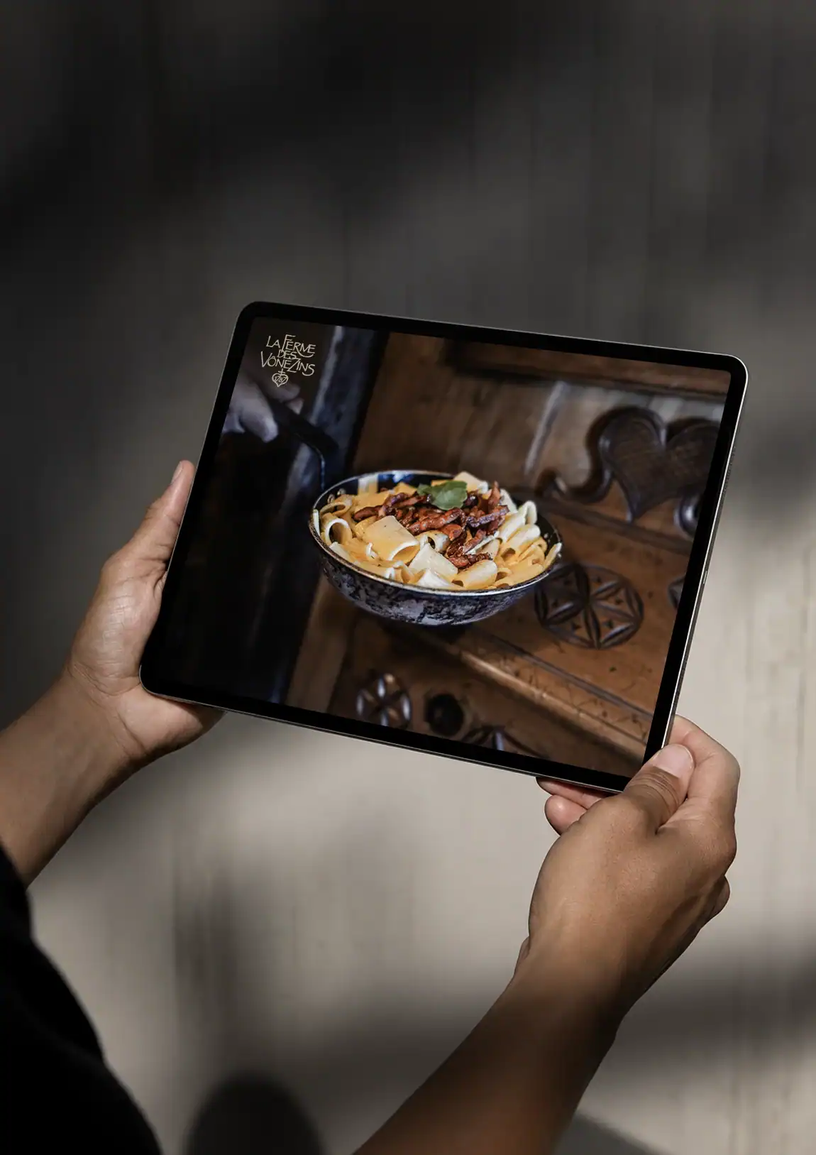 Site internet de La Ferme des Vônezins présenté sur tablette, avec une photographie de cuisine savoyarde.