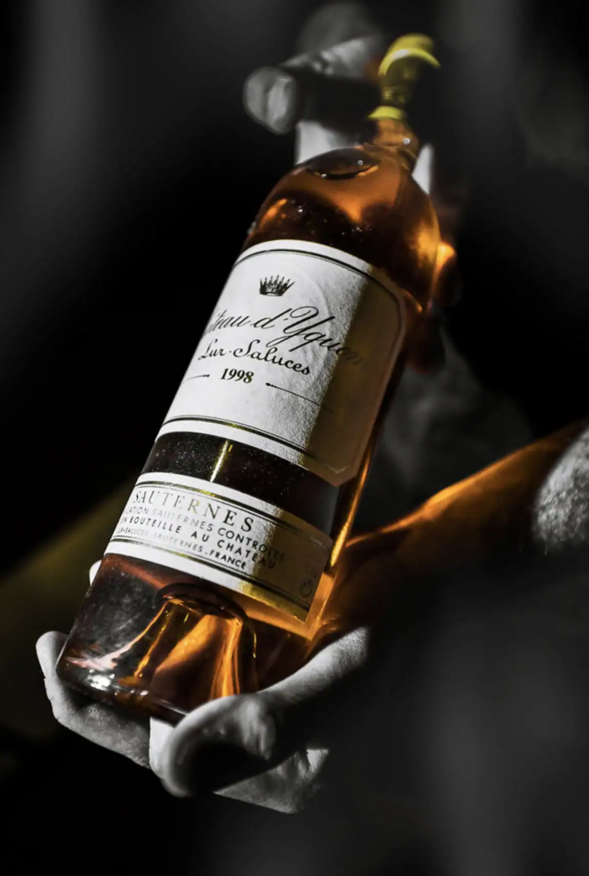 Bouteille ancienne de Ch&acirc;teau d&rsquo;Yquem tenue dans les mains lors d&rsquo;une d&eacute;gustation.