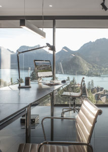 Salon avec vue sur le lac et les montagnes : Vue panoramique d'un salon moderne avec de grandes baies vitrées offrant une vue imprenable sur le lac et les montagnes à Annecy.