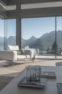 Salon avec vue sur le lac et les montagnes : Vue panoramique d'un salon moderne avec de grandes baies vitrées offrant une vue imprenable sur le lac et les montagnes à Annecy.