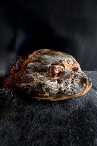 Photo produit, un magnifique jambon sur fond de pierre de la salaison Maison Alpin. Photographe à Annecy en Haute Savoie