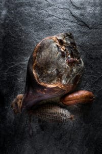 Photo produit, un magnifique jambon sur fond de pierre de la salaison Maison Alpin. Photographe à Annecy en Haute Savoie