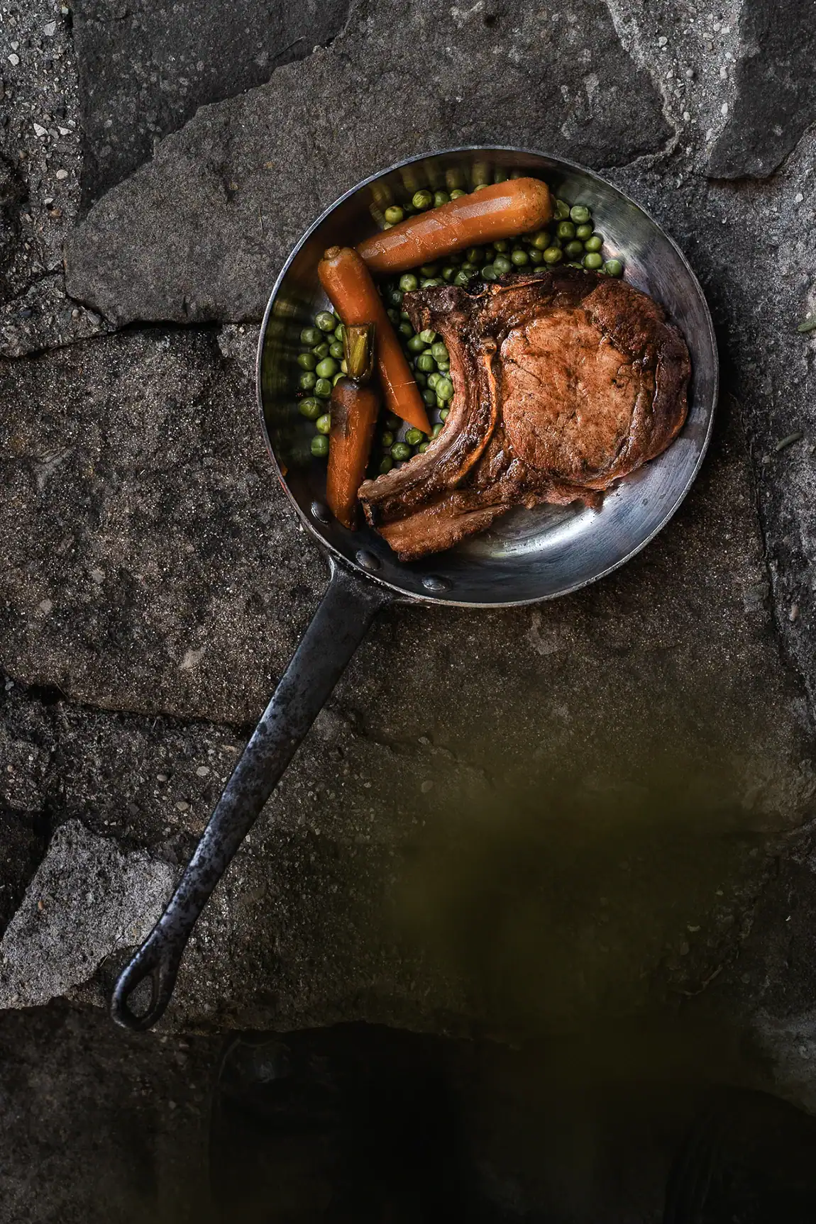 C&ocirc;te de porc Maison Alpin servie avec carottes et petits pois dans une po&ecirc;le.