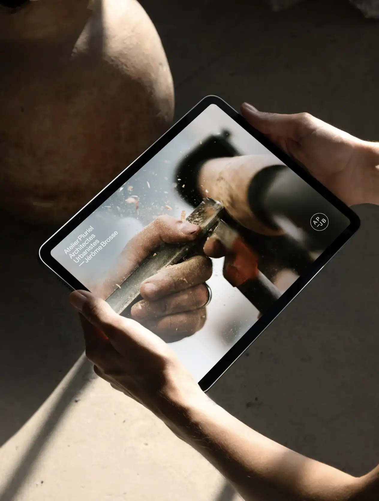 Site internet d&rsquo;Atelier Pluriel pr&eacute;sent&eacute; sur tablette avec une photographie de travail artisanal du bois