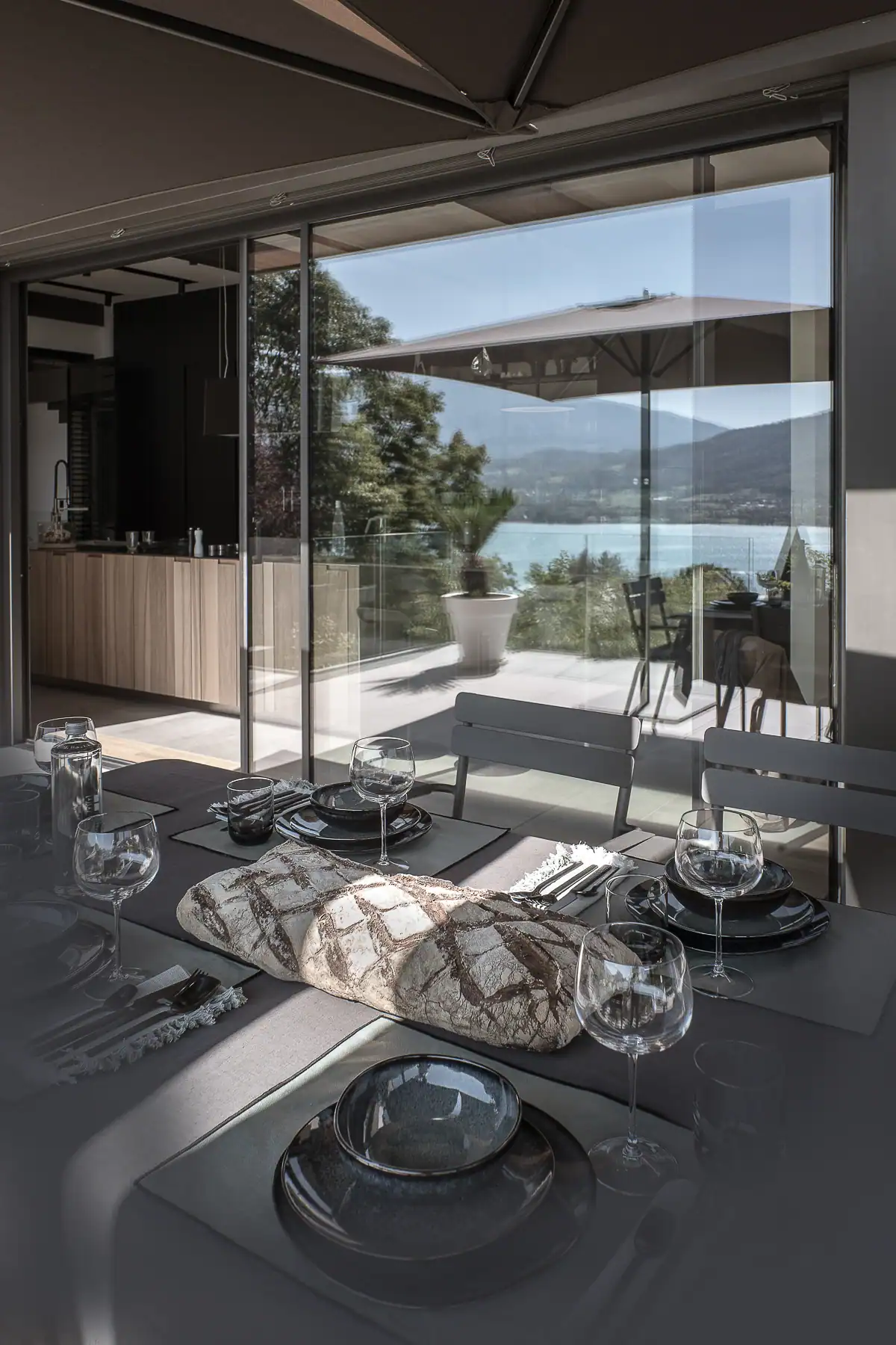 Salle à manger ouverte sur une terrasse et le lac Léman dans une villa contemporaine