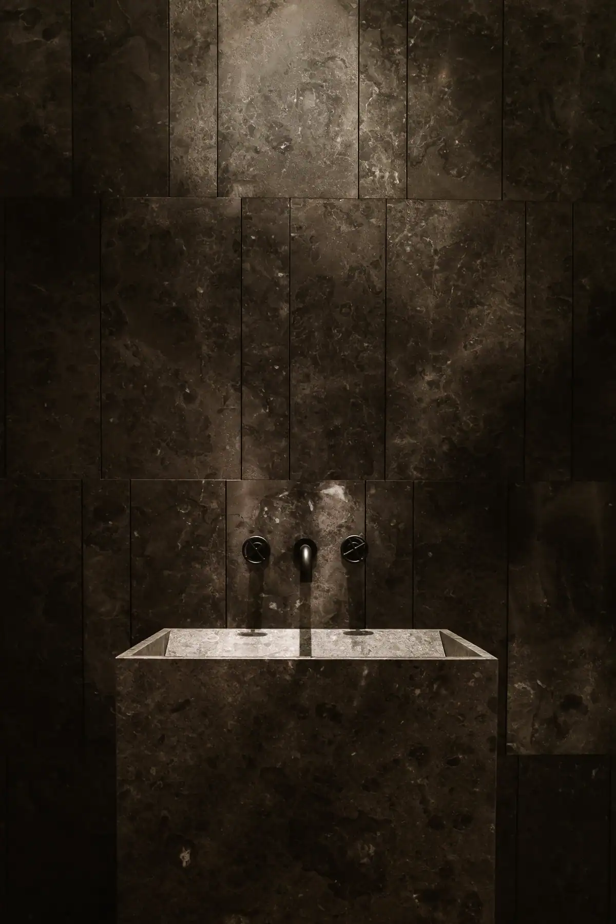 Vasque en pierre Salvatori avec robinetterie noire Fantini dans une salle de bains contemporaine