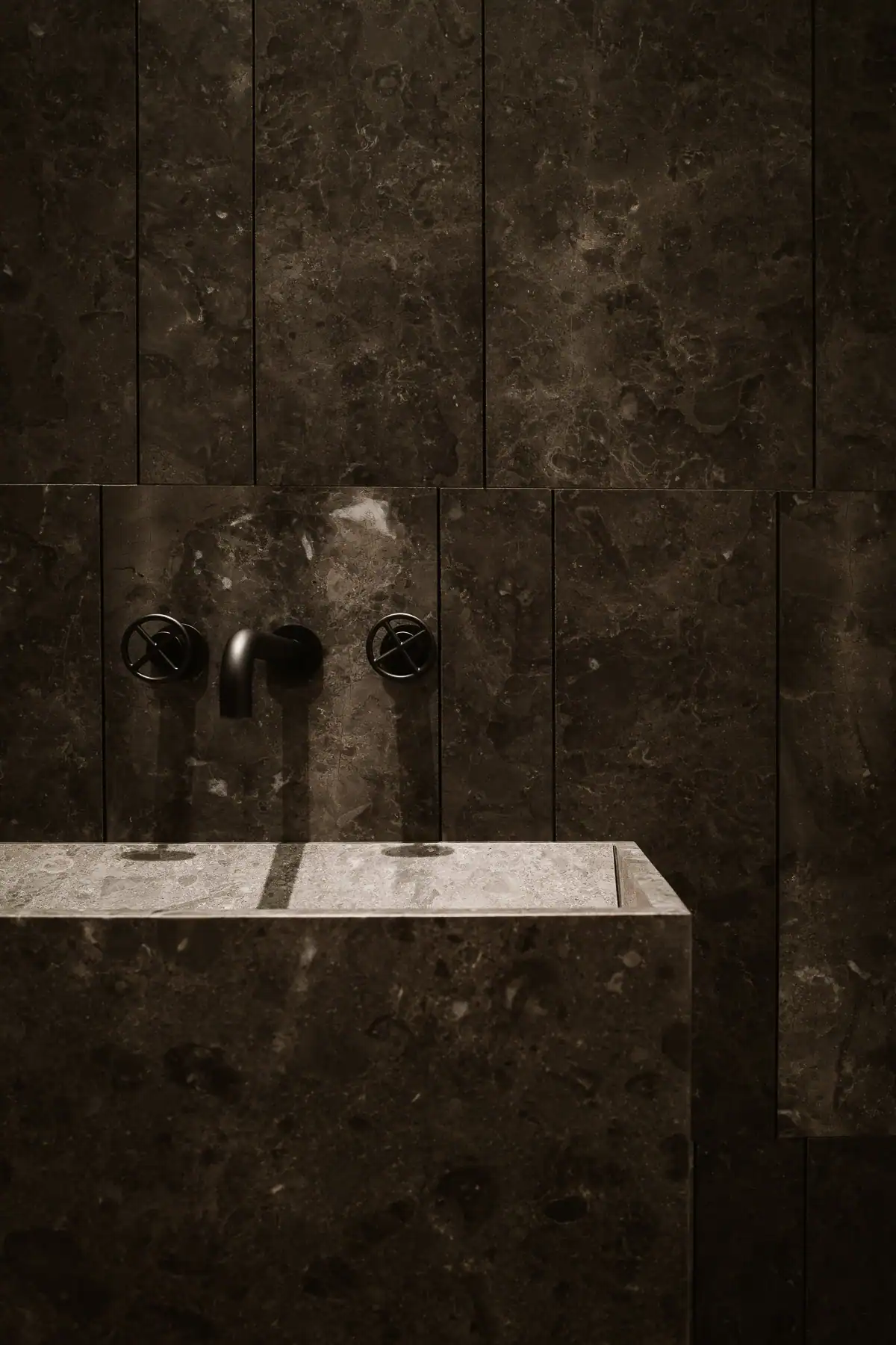 Vasque en pierre Salvatori avec robinetterie noire Fantini dans une salle de bains contemporaine