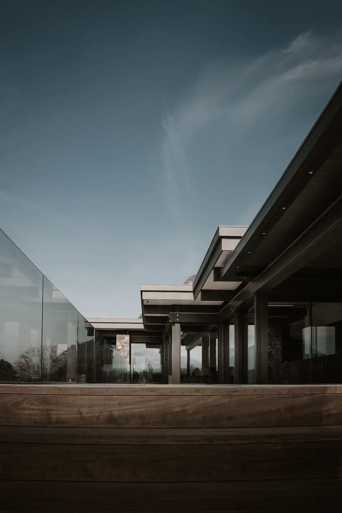 Terrasse vitrée d’une villa contemporaine proche de Genève avec structure métallique et pierre naturelle