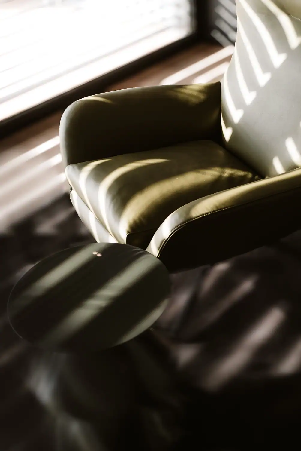 Fauteuil Minotti en cuir vert olive éclairé par la lumière naturelle