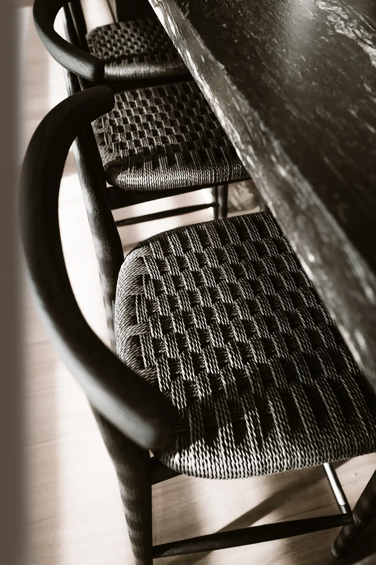 Chaises Boffi en bois sombre avec assises tressées autour d’une table en pierre