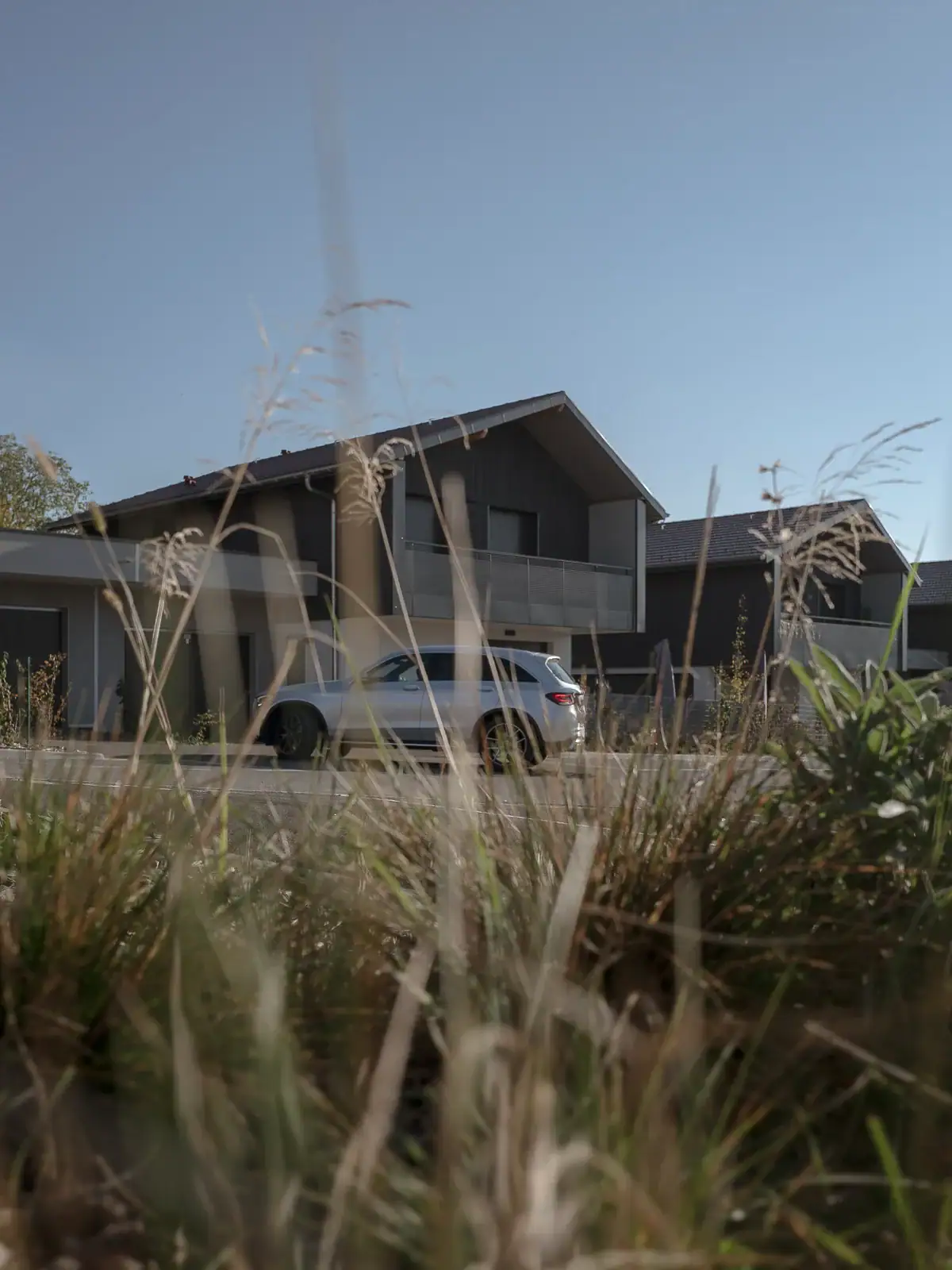 Maisons contemporaines à Versonnex, avec façades en bois, toitures à deux pans et végétation au premier plan.